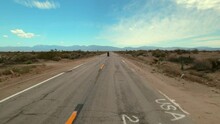Pov Forward Shot Of Man Riding Motorcycle On Road Amidst Plants In Desert Against Sky - Landers, California