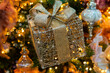 Christmas ornaments close up. Gift box with a golden bow on a decorated Christmas tree.