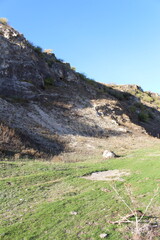 Wall Mural - A grassy hill with a rocky cliff