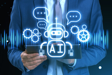 Poster - Close up of businessman hand using tablet with creative glowing robot ai hologram on dark background. Automated machine learning, artificial intelligence and conversation assistant concept.