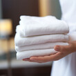 Woman holding clean white towels indoors in hotel room or spa center. 