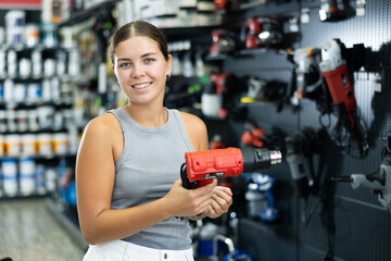 Wall Mural - Beautiful young woman chooses and buys industrial hair dryer in local hardware store