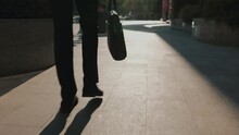 In This Dynamic Video, A Tracking Shot Provides A Close-up Of A Young Man's Legs, Walking With Style In The City's Business District. With A Wallet In Hand,