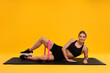 © New Africa - Woman exercising with elastic resistance band on fitness mat against orange background