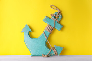 Wall Mural - Anchor with hemp rope on white wooden table near yellow wall