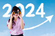 © Creativa Images - Female entrepreneur using binoculars with the 2024 new year numbers