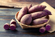 Purple sweet potato in basket on wooden background