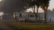 Rv motorhome parked at campsite early morning with sunlight shineing on vehicle 