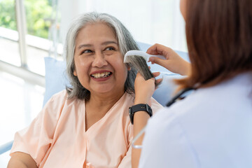 Close-up photo of an nurse combs the hair of an elderly Asian patient and offers a pep talk.