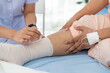 © pixs4u - Close-up photo of an Elderly Asian patient admitted to hospital A nurse cares for a patient's injured leg bandage.