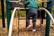 Toddler Boy Climbing on Chain Ladder on Playground in Fall