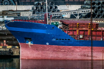 The front of a red and blue ship close up in port