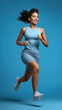 Young woman in sport wear and running on blue background.