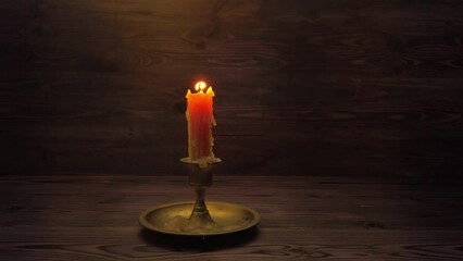 Wall Mural - burning old candle with vintage brass candlestick on wooden background in minimalist room interior