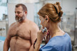 Female doctor listening to heartbeats and rhytm of overweight patient using stethoscope, detecting murmurs, irregularities, heart palpitations. Obesity affecting middle-aged men's health. Concept of
