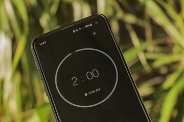 A phone with a black and white 2-minute timer to study with the pomodoro method on a blurry background