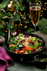 Canvas Print - Christmas or New Year table. Winter salad with beetroot, oranges, walnuts, pomegranate, dried cranberries, valerian lettuce, blue cheese. Pink wine in glass. Honey dressing. Christmas tree.