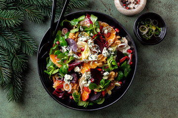 Wall Mural - Top view of winter Christmas salad with beetroot, oranges, walnuts, pomegranate, dried cranberries, lettuce, blue cheese. Spices. Honey and olive oil dressing.