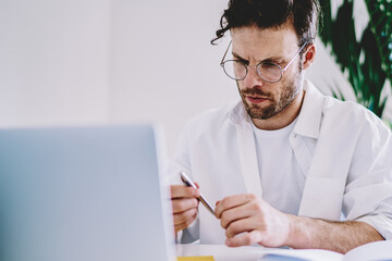 Poster - Pensive caucasian male designer concentrated on analyzing information during work
