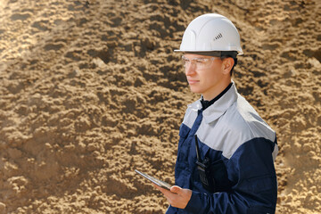 Engineer man use computer tablet for control quality of sand on quarry industrial open pit mine or cement plant