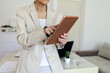 © Jelena Stanojkovic - Happy mature female architect sitting at her office desk and using a digital tablet. Experienced female working on a project at her office using a tablet computer.