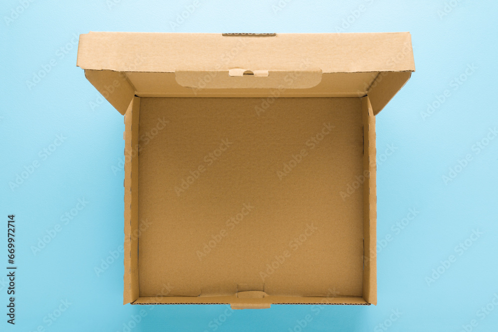 Opened empty brown carton box on light blue table background. Pastel ...