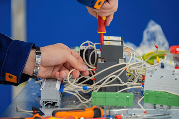 Poster - hands of electrician with screwdriver. foreman repairs power shield. electrician hands among wires a