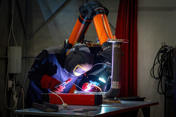 Poster - Welder repairs pipe. Man with soldering machine. Welder in mask in workshop. Craftsman seals hole in pipe. Fragment pipeline on welder table. Worker works in production facility. Soldering specialist
