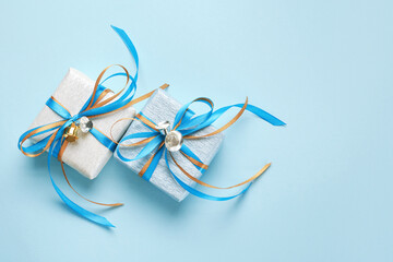 Wall Mural - Two gift boxes wrapped in white and blue silver paper with blue and gold ribbon bows and bells. Blue background, top view. Christmas and New Year gifts, Boxing Day.