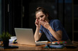 © Wasana - businesswoman yawning while working with a laptop computer. Feeling bored and tired.