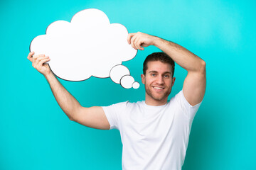 Wall Mural - Young caucasian man isolated on blue background holding a thinking speech bubble