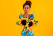 Woman With Pair Of Sunflowers Against Yellow Background