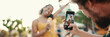 © Andrii Nekrasov - Close-up of a man taking a picture of a woman on a mobile phone. Closeup, smiling woman eating ice cream and filming it with smartphone on urban city background. Backlight