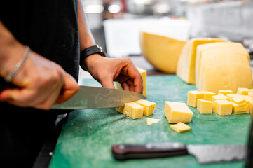 Wall Mural - man chef cutting cheese on dices with knife on kitchen