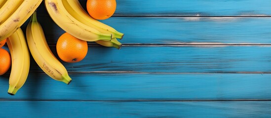 Bananas and oranges displayed on a blue wooden background