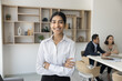 © fizkes - Cheerful manager girl posing with arms folded in office meeting room, looking at camera, smiling, enjoying career, leadership, job in successful company. Confident young business woman portrait