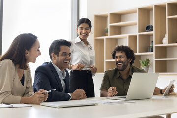 Poster - Cheerful Indian and Arab business colleagues laughing at laptop, having fun, relaxing, brainstorming on creative ideas, getting motivation, inspiration, ejoying teamwork spirit, joke, humor