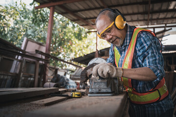 Wall Mural - An elderly carpenter works the wood with meticulous care.