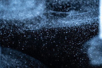Wall Mural - blue particles on black background with cinematic atmosphere. glittering sparkling bokeh overlay wit