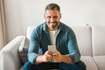 Poster - Happy middle aged european man using mobile phone at home