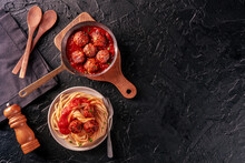 Meatballs. Beef meat balls, overhead flat lay shot in a pan and with a plate of spaghetti pasta, on a black background, with copy space