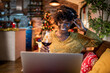 © Marko Geber - Young woman working on her laptop in a cozy living room with Christmas decorations