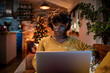 © Marko Geber - Young woman working on her laptop in a cozy living room with Christmas decorations