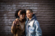© Marko Geber - Portrait of lesbian couple hugging each other with a brick wall background