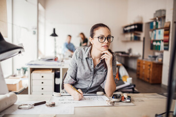 Thoughtful architect pondering over design blueprints in a vibrant workspace