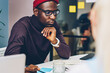 © BullRun - Serious african american hipster guy in spectacles concentrated on reading information during lesson