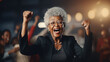 Excited elderly businesswoman celebrating success in office. Cheerful mature woman looking at camera with open mouth and hands raised. Happy african american female senior rejoices achievement