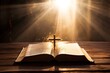 An open Bible and a cross on a wooden table in the sunlight