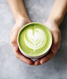 Female hands holding a cup of matcha latte