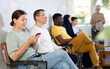 © JackF - Positive woman communicates on mobile phone while sitting on chair in the company office waiting for a specialist
